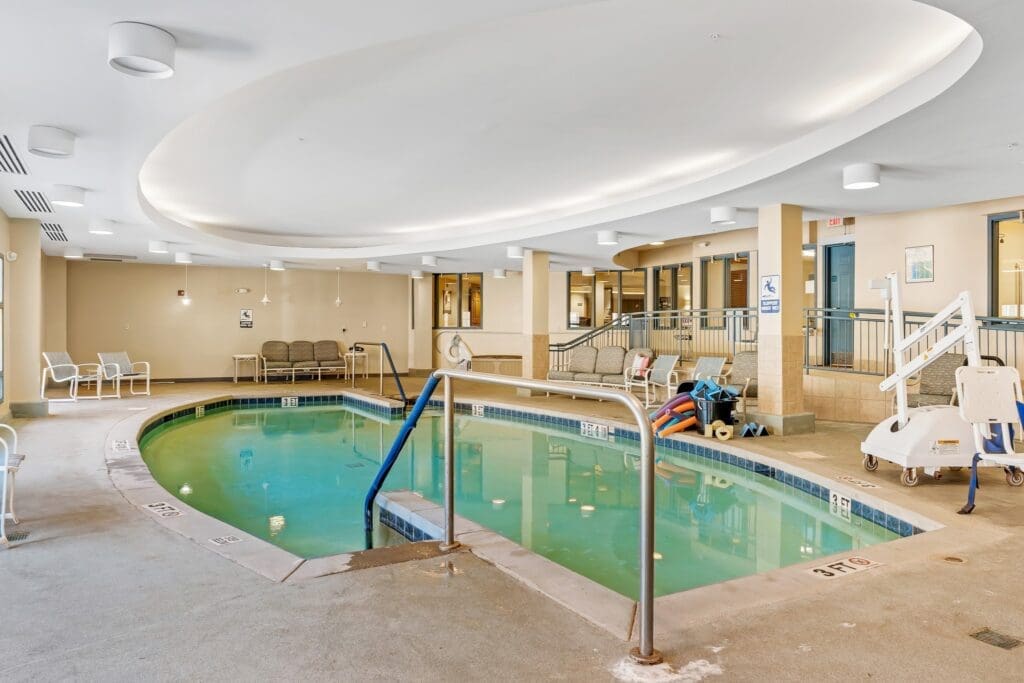 Indoor pool area featuring accessible entry, seating, and vibrant ambiance, promoting wellness and relaxation.