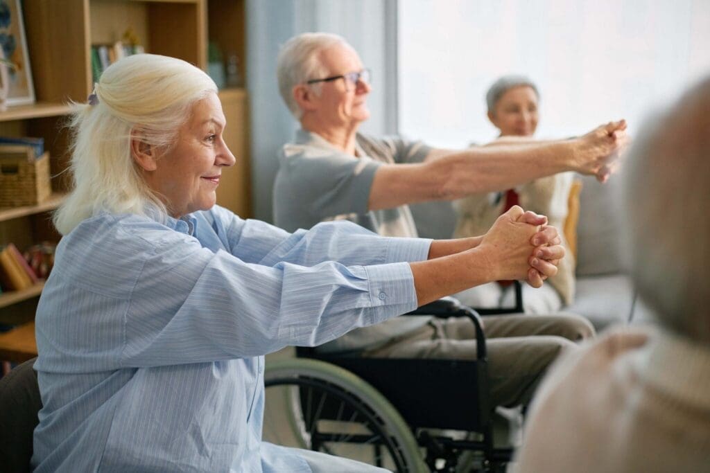 Seniors engaging in a group exercise session, smiling and stretching in a bright, inviting living space.