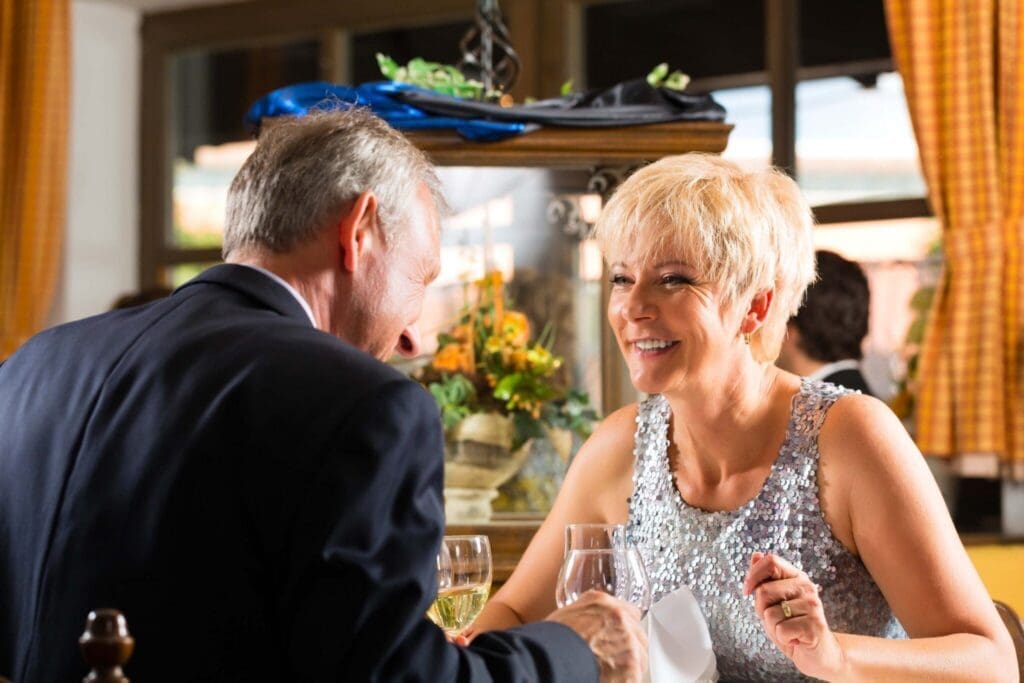 Joyful couple dining together in an elegant restaurant, sharing laughter and a celebratory toast.