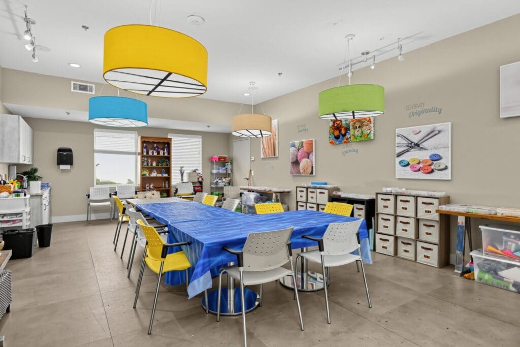 Bright, inviting activity room with a long table, colorful chairs, and art supplies for creative engagement.