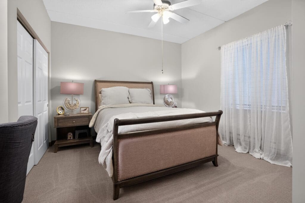 Elegant, well-appointed bedroom featuring a plush bed, stylish nightstands, and inviting natural light through sheer curtains.
