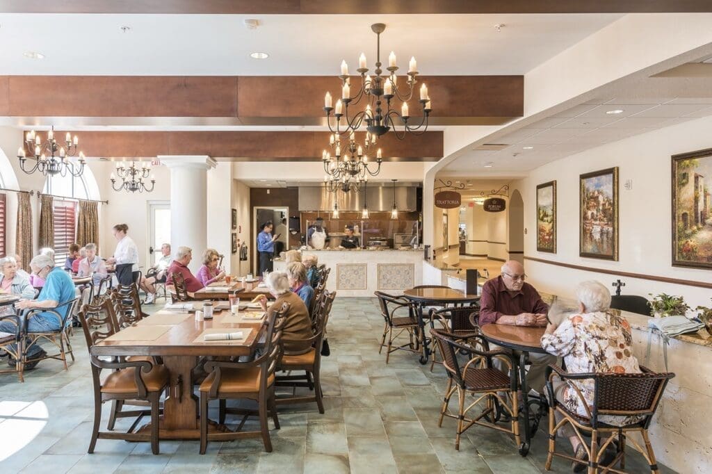 Bistro-Large - Grace Management Seniors enjoy a vibrant dining experience in an upscale dining area with elegant chandeliers and attentive service.