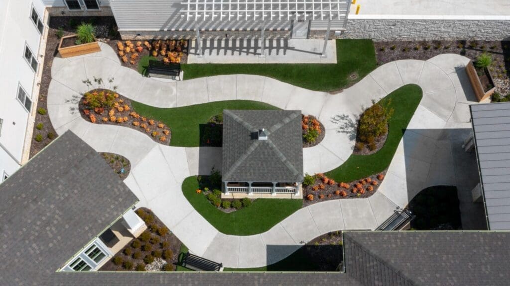 Lush courtyard featuring winding pathways, vibrant flowers, and a central gazebo, promoting an inviting, serene outdoor experience.