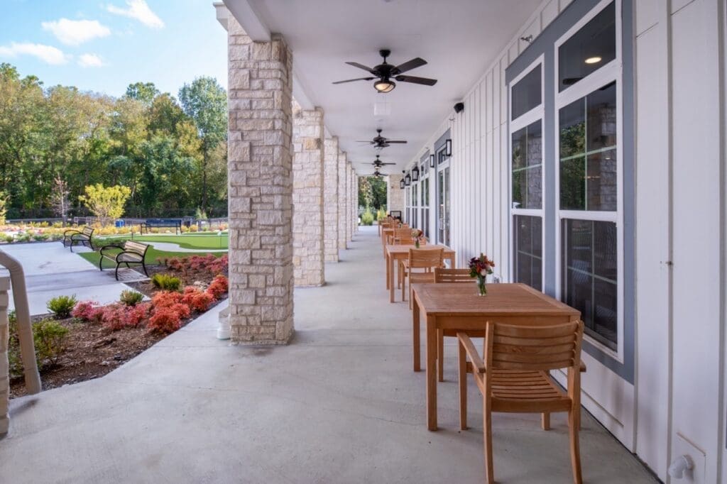 Inviting outdoor seating area with wooden tables and chairs, surrounded by lush landscaping and a vibrant courtyard.