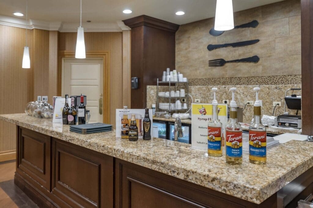 Upscale bar area featuring a granite countertop, assorted beverages, and stylish lighting, promoting a vibrant social atmosphere.