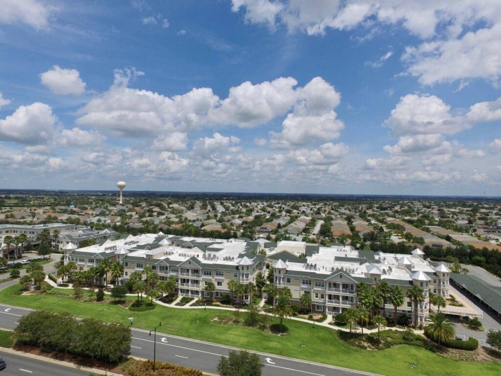 Vibrant senior living community featuring elegant buildings, lush greenery, and expansive skies under a bright, sunny atmosphere.