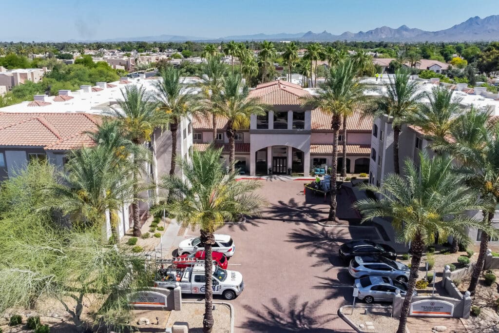 DJI_0288-11205270 - Grace Management Elegant senior living community entrance, surrounded by palm trees and upscale landscaping, showcasing vibrant, welcoming atmosphere.