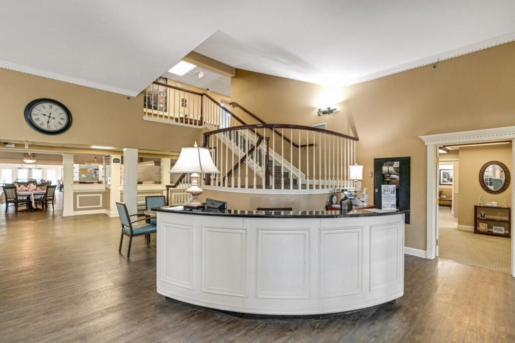 Inviting reception area featuring elegant decor, a staircase, and dining space, embodying a vibrant senior living environment.