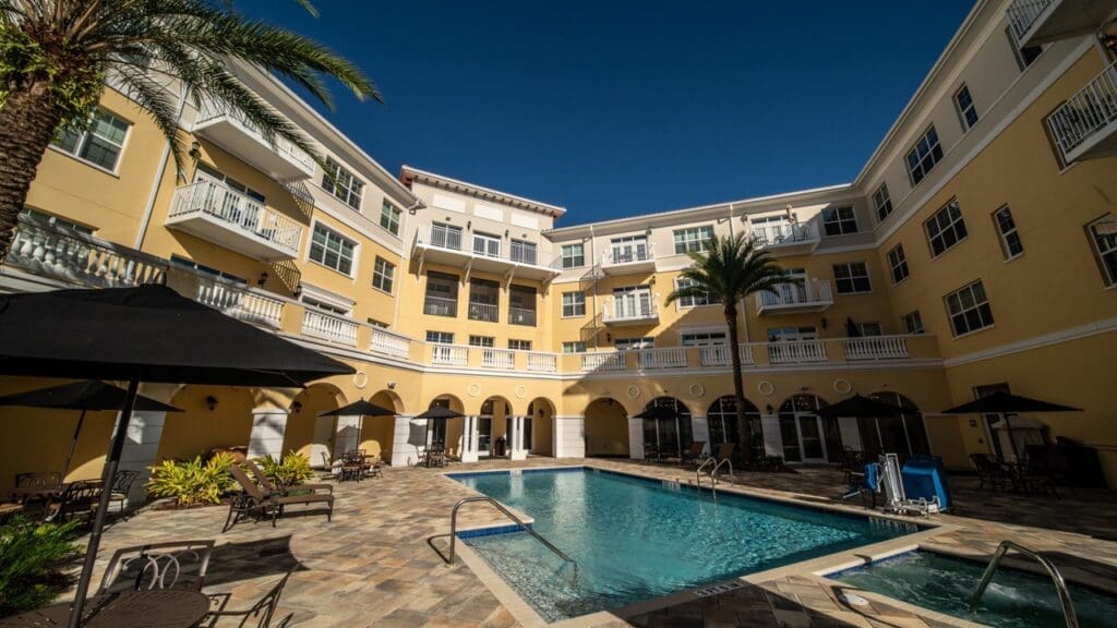 DSC5061 - Grace Management Vibrant courtyard featuring a sparkling pool surrounded by elegant seating and lush landscaping under a clear blue sky.