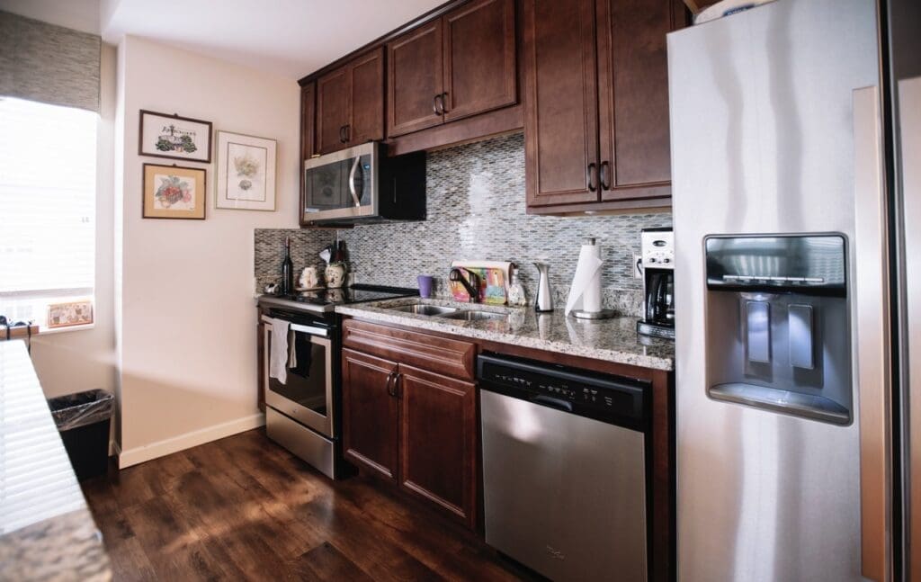 DSC5757-Large - Grace Management Stylish kitchen with modern appliances, granite countertops, and warm wooden cabinetry, radiating elegance and comfort.