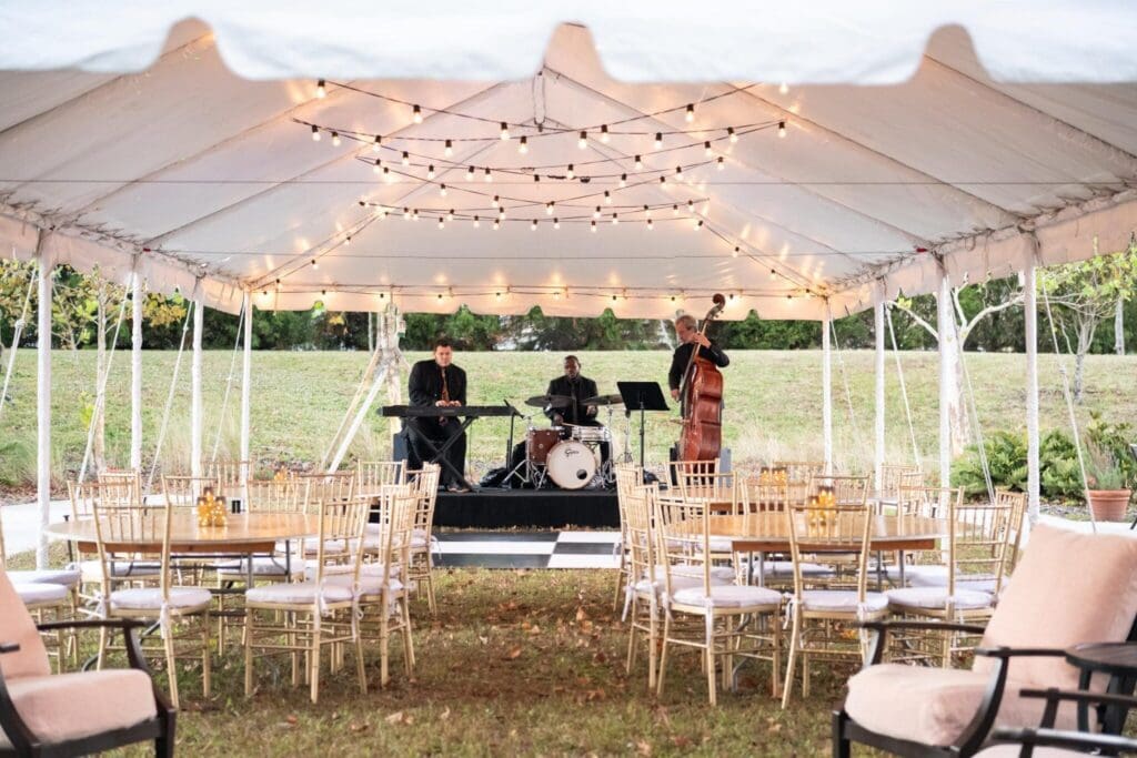 Stylish outdoor event tent with elegant seating, featuring live musicians creating a sophisticated atmosphere.