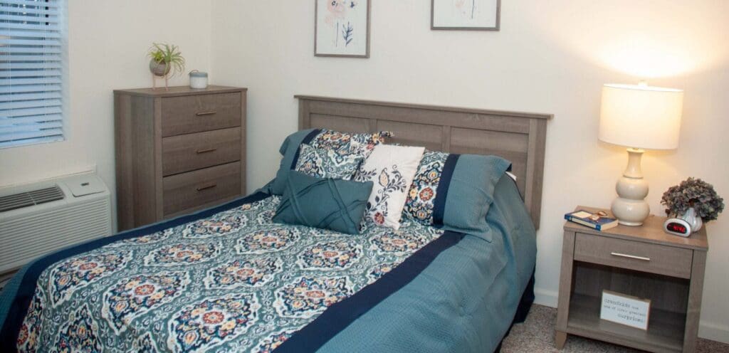 Bright, cozy bedroom featuring a decorated bed, bedside table, and elegant accessories, promoting a warm, inviting atmosphere.