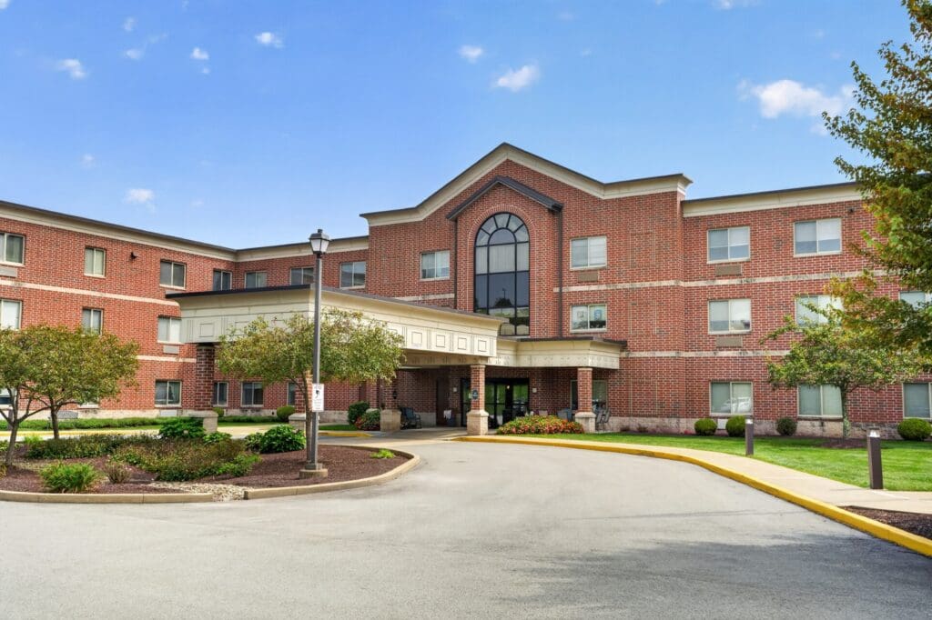 Elegant senior living community entrance, featuring inviting landscaping and a welcoming facade under a clear blue sky.