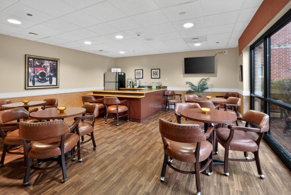 Welcoming lounge with stylish leather seating, round tables, a modern bar area, and large windows for natural light.