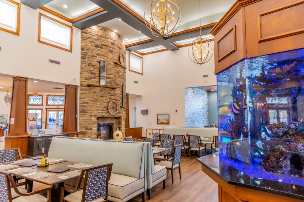 Elegant dining area featuring plush seating, a beautiful stone fireplace, and a vibrant aquarium, evoking a welcoming ambiance.