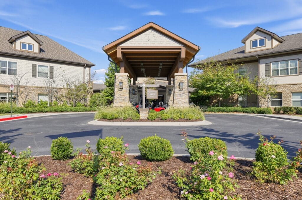 Welcoming entryway of an upscale senior living community, featuring stone architecture and vibrant landscaping.
