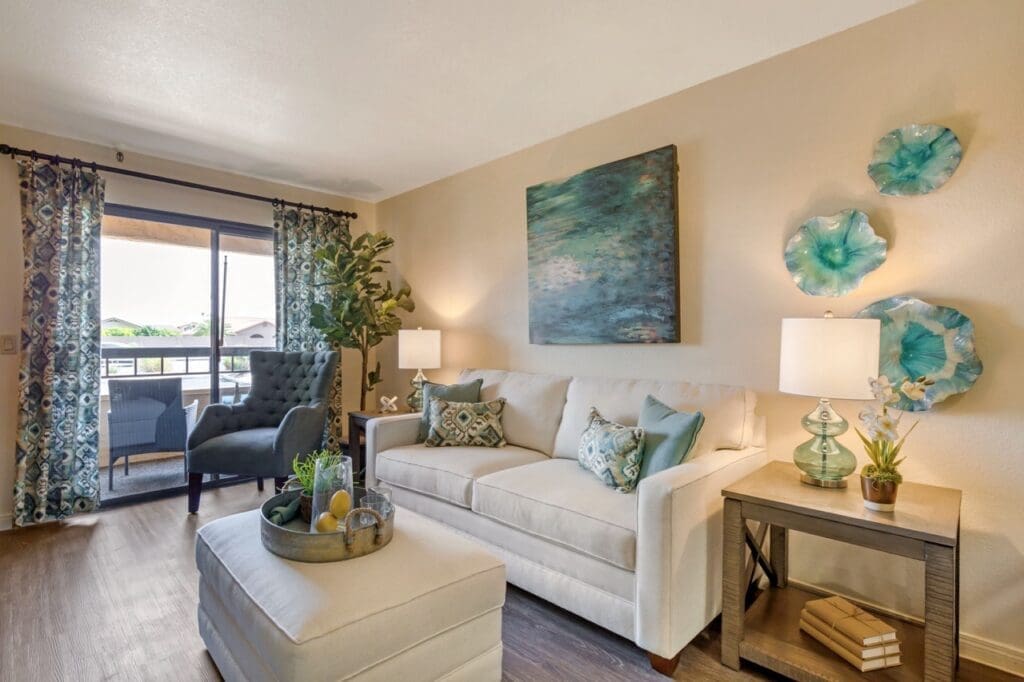 Final-Selects-303A5217-Large - Grace Management Bright, inviting living room with elegant furnishings, vibrant decor, and large windows showcasing a view of outdoor greenery.