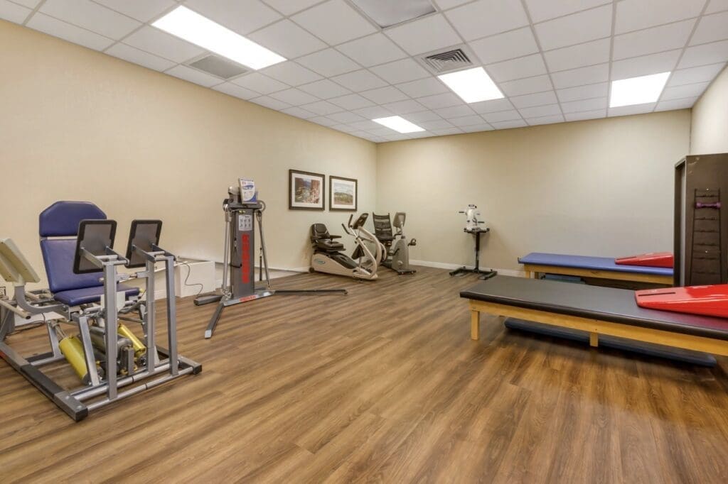Final-Selects-303A5333-Large - Grace Management Well-equipped fitness area featuring exercise machines, therapy tables, and a welcoming atmosphere for active lifestyles.