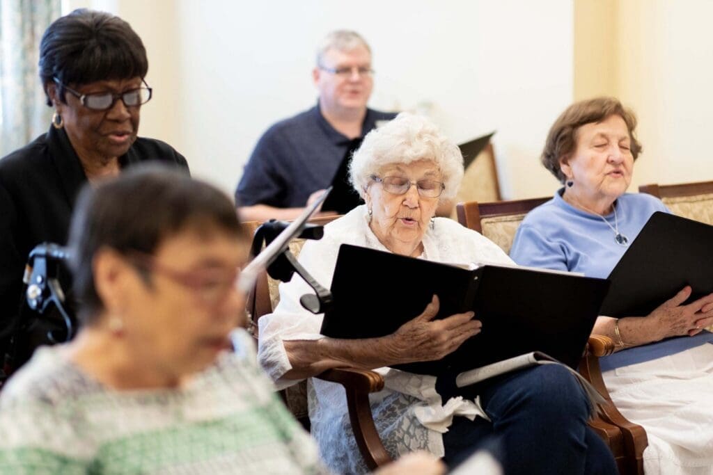 Residents enjoy a joyful singing session, sharing smiles and music in a warm, inviting community space.