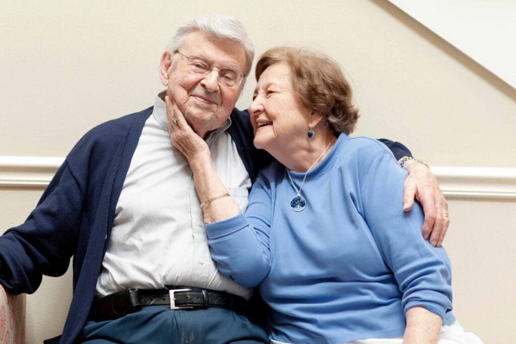 An elderly couple shares a joyful moment, embracing and smiling warmly, radiating love and companionship.