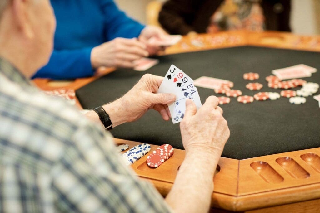Seniors enjoying a lively poker game, with cards and chips on a sleek gaming table, fostering social engagement and camaraderie.