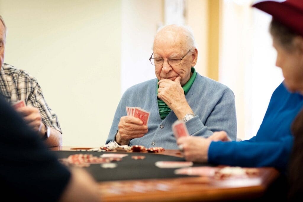 Seniors enjoying a spirited poker game, showcasing camaraderie and engagement in a welcoming community setting.