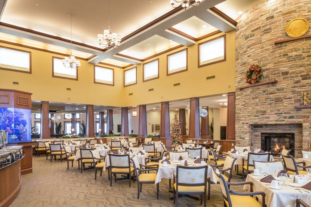 Elegant dining area featuring tables set for gourmet meals, a festive holiday tree, and a cozy fireplace.