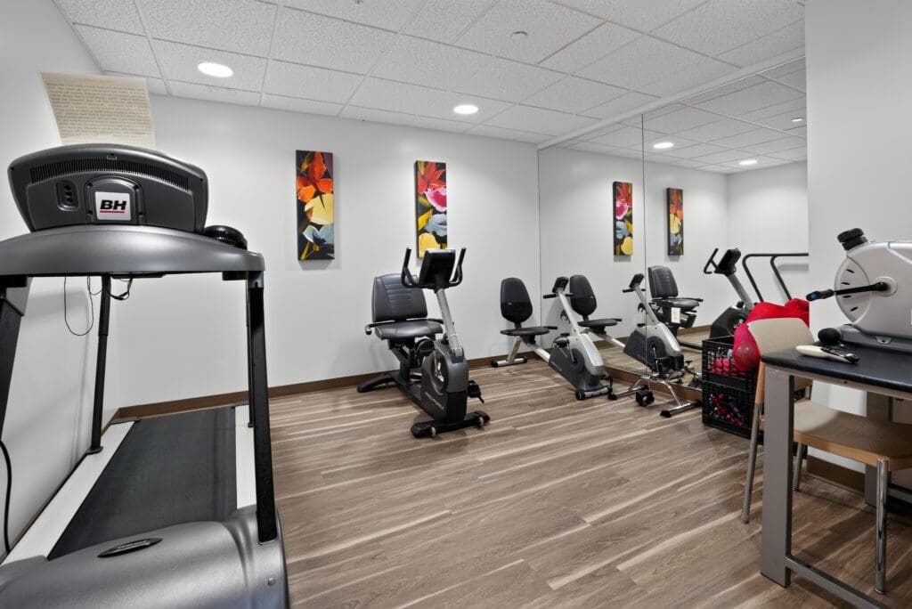 Modern fitness center featuring diverse exercise equipment and vibrant wall art, promoting an active, healthy lifestyle.