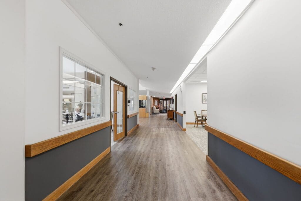 Hallway_NorthgatePark - Grace Management Bright, spacious hallway in a senior living community featuring elegant decor and warm wood accents.