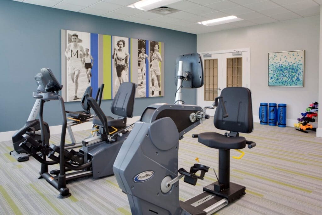 Heritage-Oaks1828-2048x1366 - Grace Management Modern fitness center featuring advanced exercise equipment, vibrant decor, and inspiring wall art of runners.