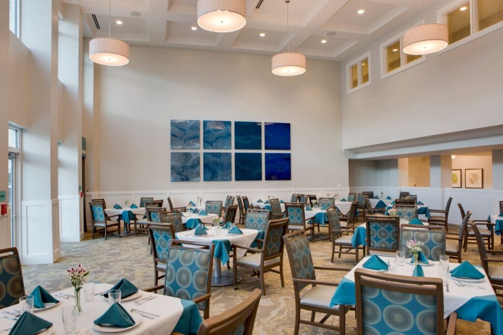 Heritage-Oaks1844-2048x1366 - Grace Management Elegant dining area featuring tables set with teal accents, surrounded by spacious, light-filled surroundings and contemporary art.