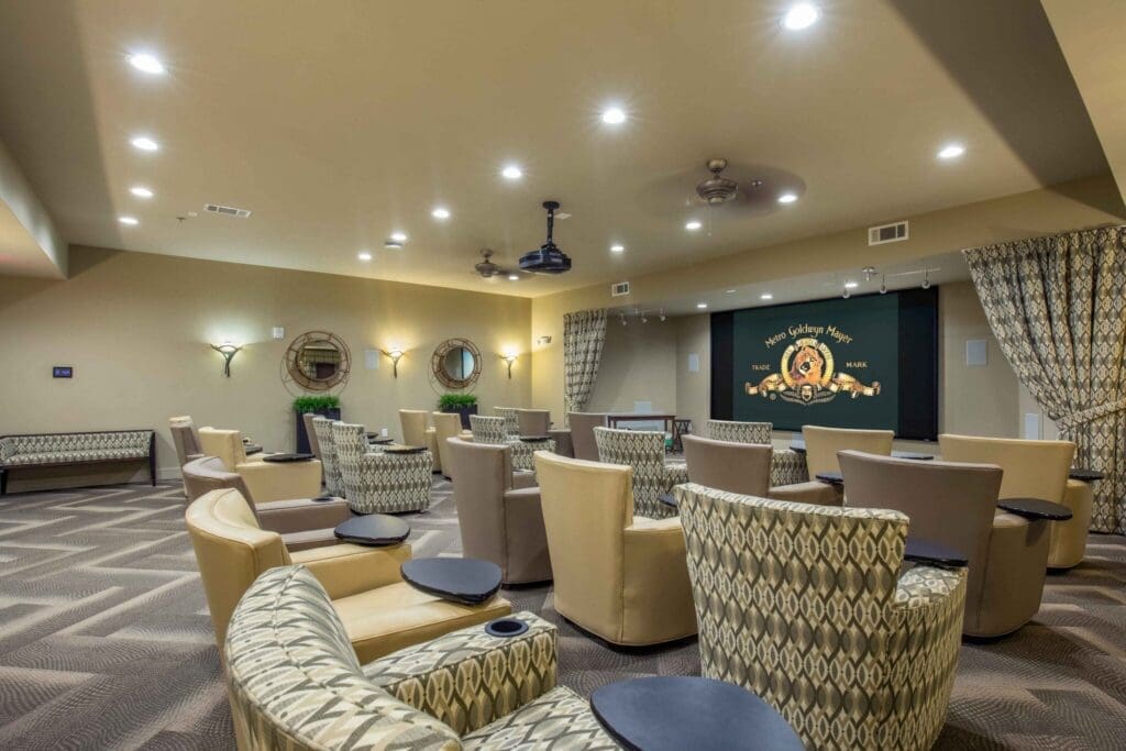 Stylish theater room with inviting seating, elegant decor, and a large screen, perfect for a vibrant senior lifestyle.