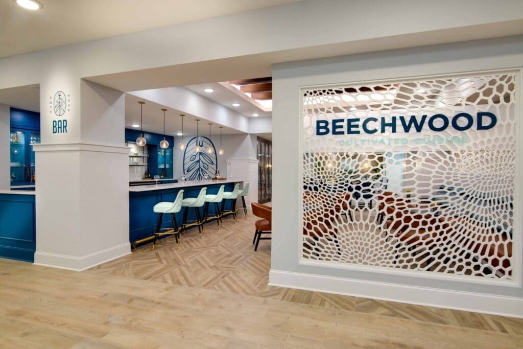 IL-Beechwood-Lounge-2-2048x1365 - Grace Management Elegant bar area featuring vibrant blue cabinetry, stylish seating, and the Beechwood Cultivated Cuisine sign.