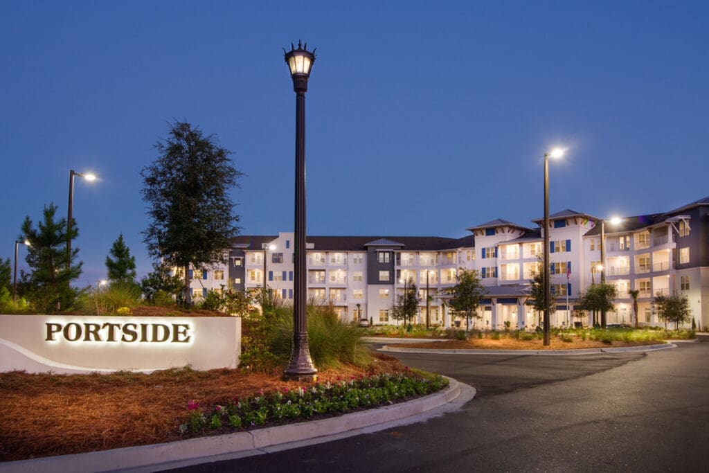 IL-Entry-sign-edited - Grace Management Elegant senior living community exterior at dusk, featuring lush landscaping and illuminated architecture.