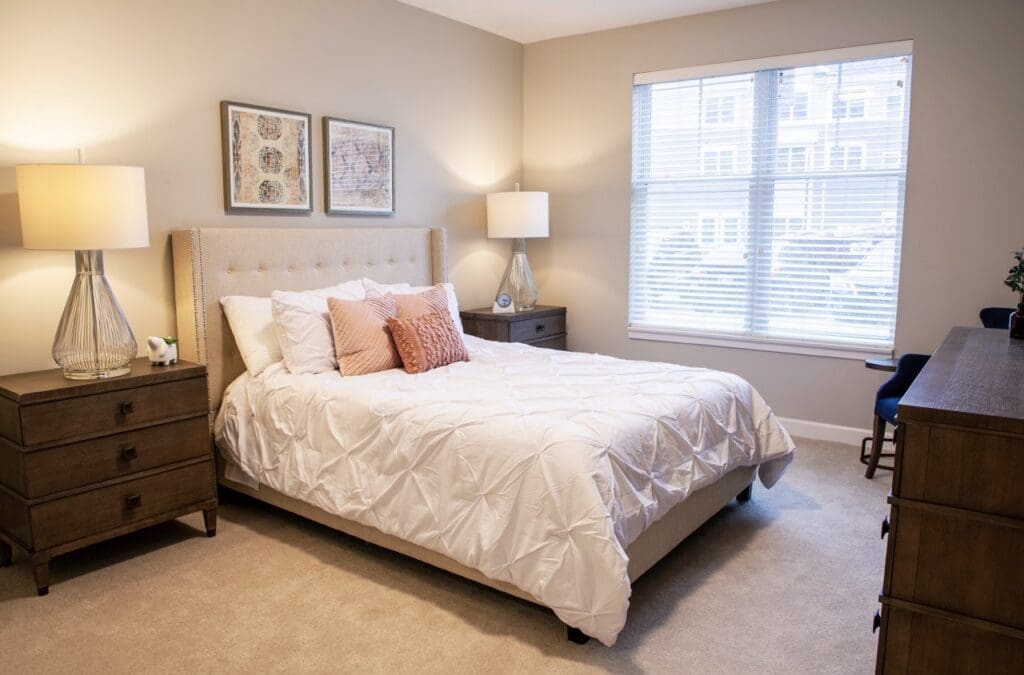 IMG_9738-HDR-Large - Grace Management Elegant bedroom featuring a plush white bed, stylish decor, warm lighting, and a bright window overlooking a serene landscape.