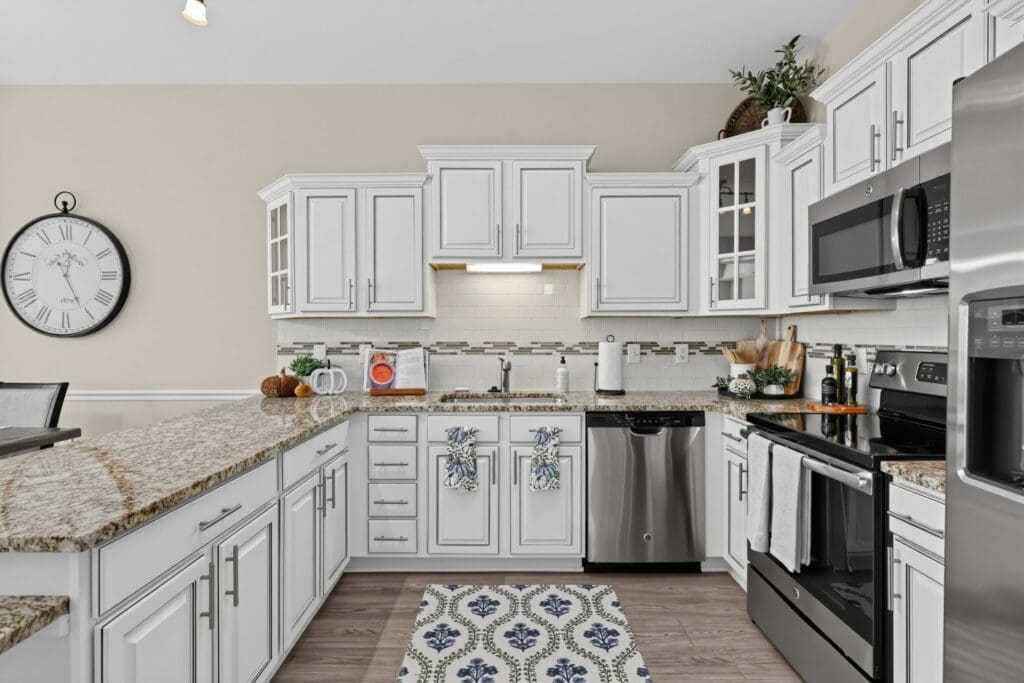 Stunning, modern kitchen featuring white cabinetry, sleek appliances, granite countertops, and elegant decor elements.