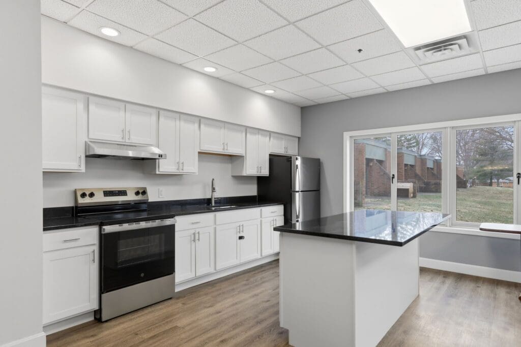 Kitchen_NorthgatePark - Grace Management Modern kitchen featuring stainless steel appliances, sleek cabinetry, and large windows offering a view of the outdoors.
