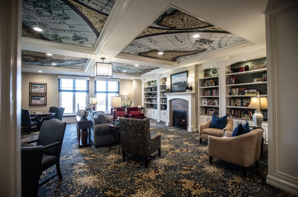 Library-1-2048x1356 - Grace Management Elegant common room featuring plush seating, a cozy fireplace, and beautiful décor, promoting an inviting, vibrant atmosphere.