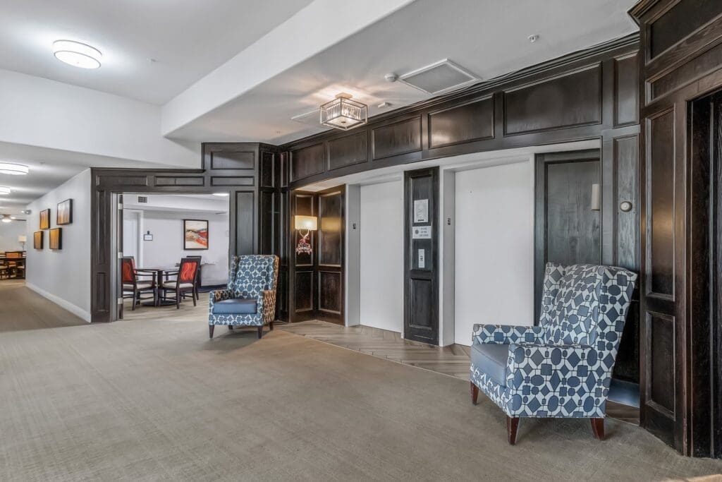 MG_4461 - Grace Management Elegant lobby area featuring comfortable seating, modern decor, and doors leading to elevators and a dining area.