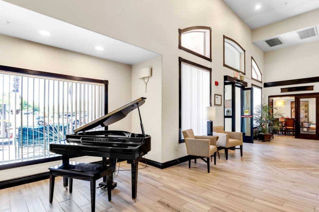 MG_4488 - Grace Management Elegant lobby featuring a black grand piano, cozy seating, and bright natural light from large windows.