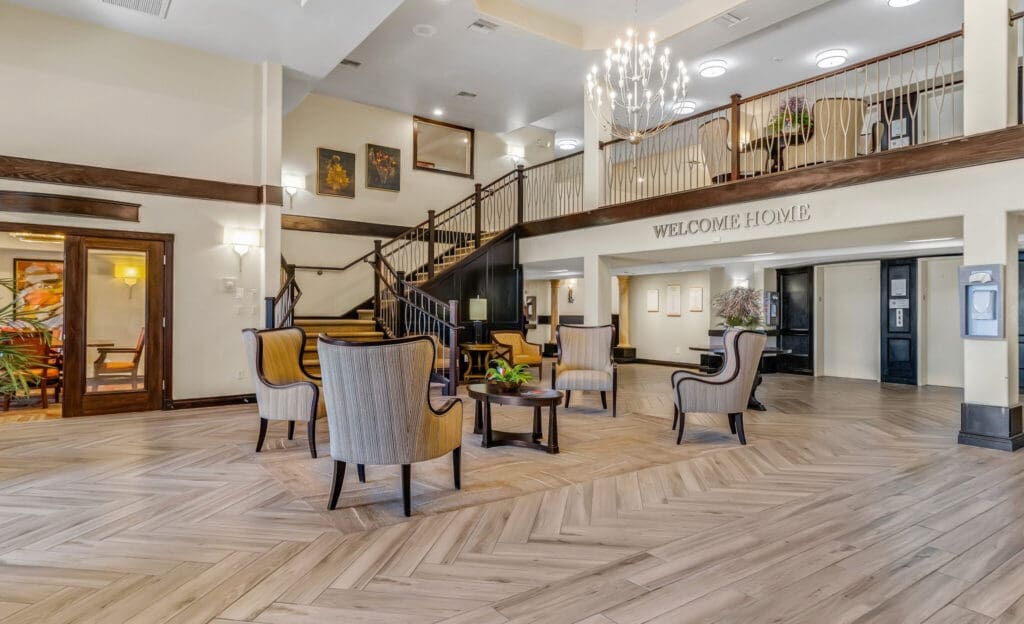 MG_4491-e1687984433378 - Grace Management Elegant lobby featuring welcoming seating, a grand staircase, and tasteful decor, embodying a vibrant senior living atmosphere.