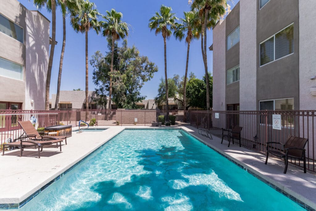 MG_4507-11205351 - Grace Management Inviting pool area surrounded by palm trees and lounge chairs, offering a serene outdoor oasis for residents.