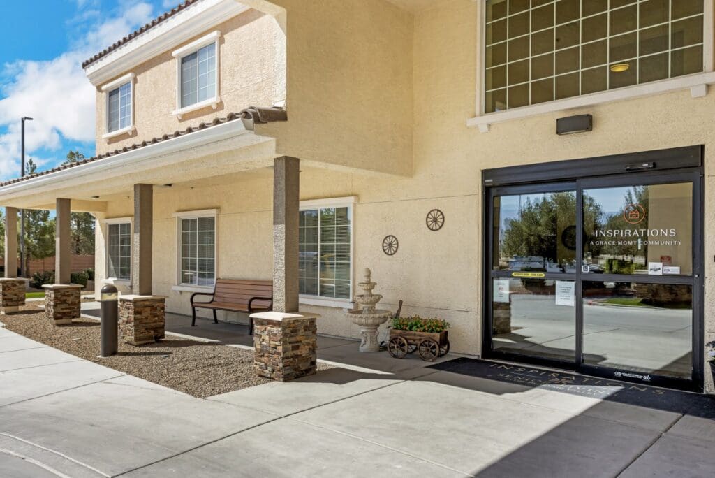 Welcoming entrance of Inspirations community featuring stone pillars, seating, and vibrant landscaping under a bright sky.