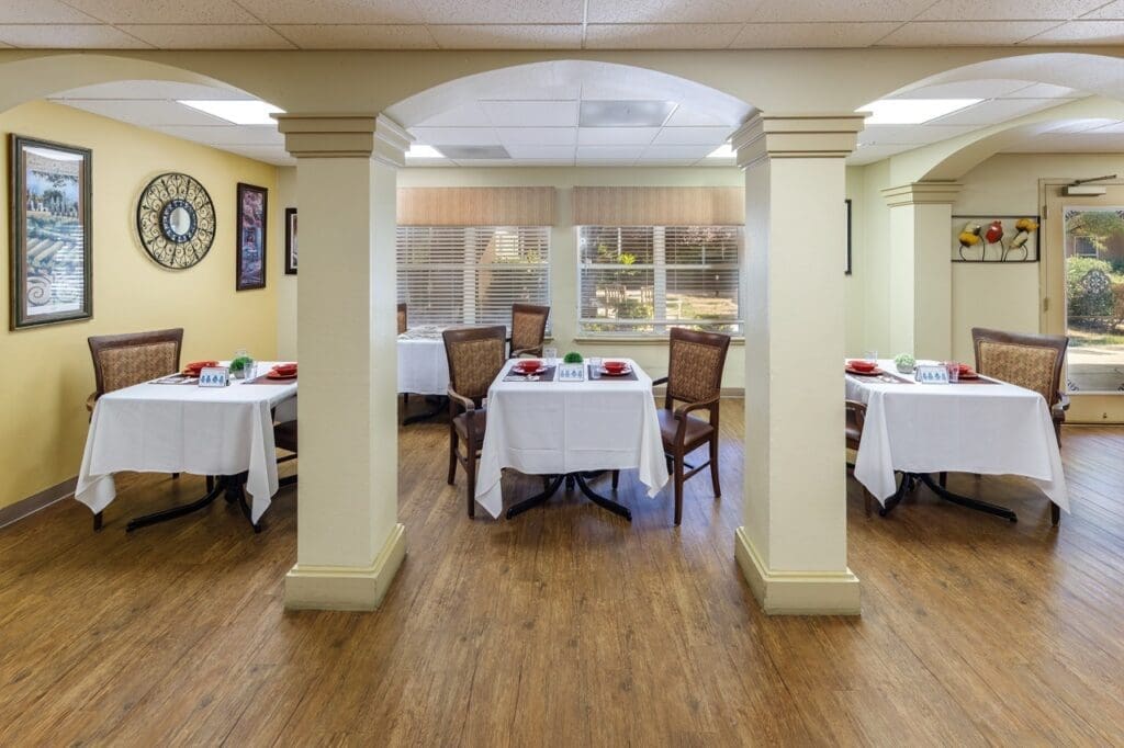 Elegant dining area featuring neatly set tables with white linens and tasteful decor, promoting a vibrant social atmosphere.