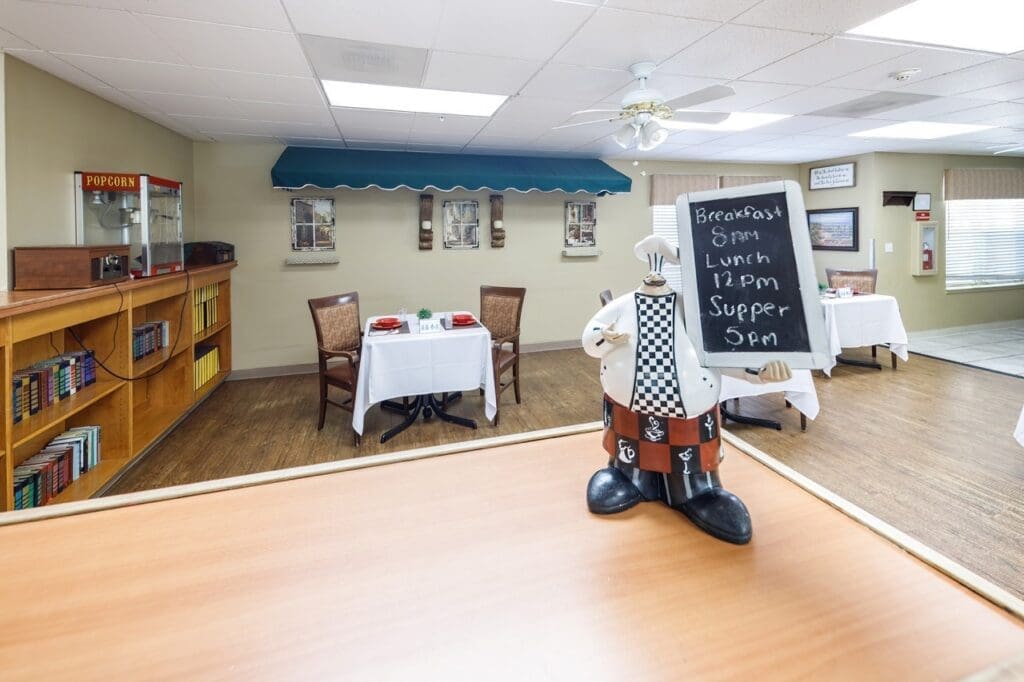 Bright dining area featuring elegant seating, a whimsical chef statue, and a menu board highlighting meal times.