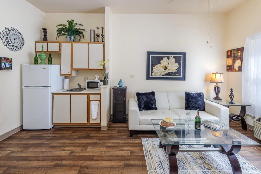 Elegant living space featuring a cozy white sofa, modern kitchenette, and tasteful décor, embodying comfort and style.