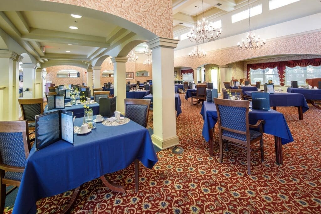 Elegant dining area with blue tablecloths, fine china, and floral decor, inviting a vibrant, upscale dining experience.