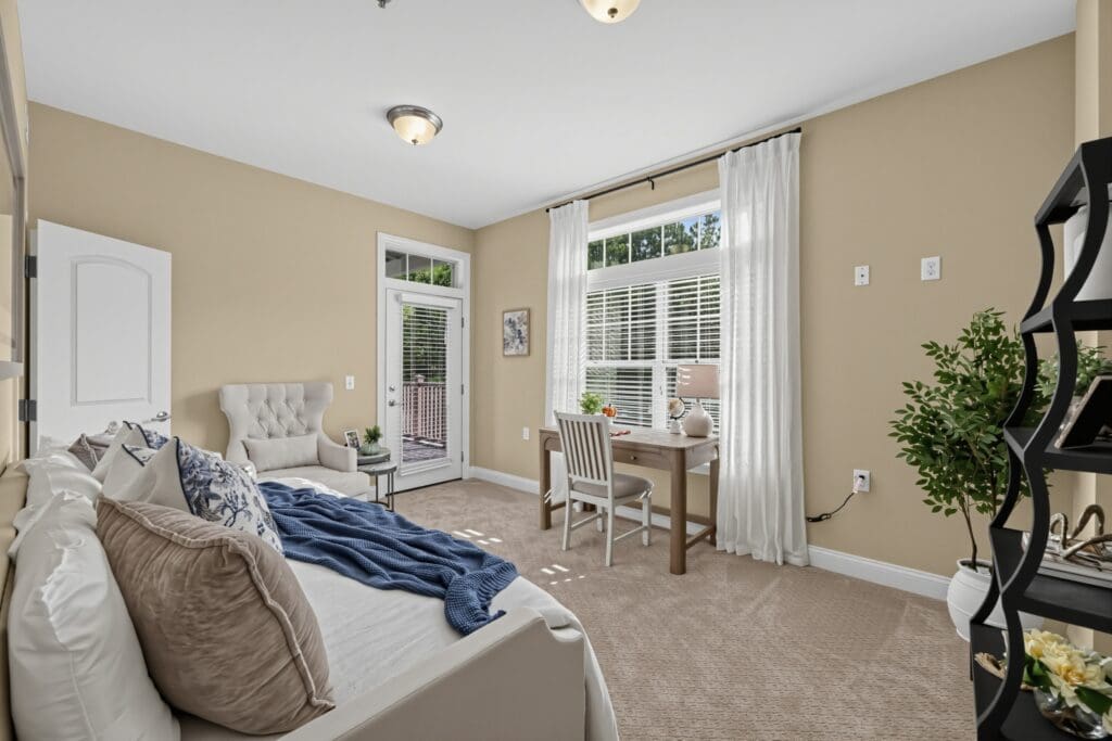 Spacious, elegantly furnished room featuring natural light, a cozy seating area, desk, and access to a private balcony.