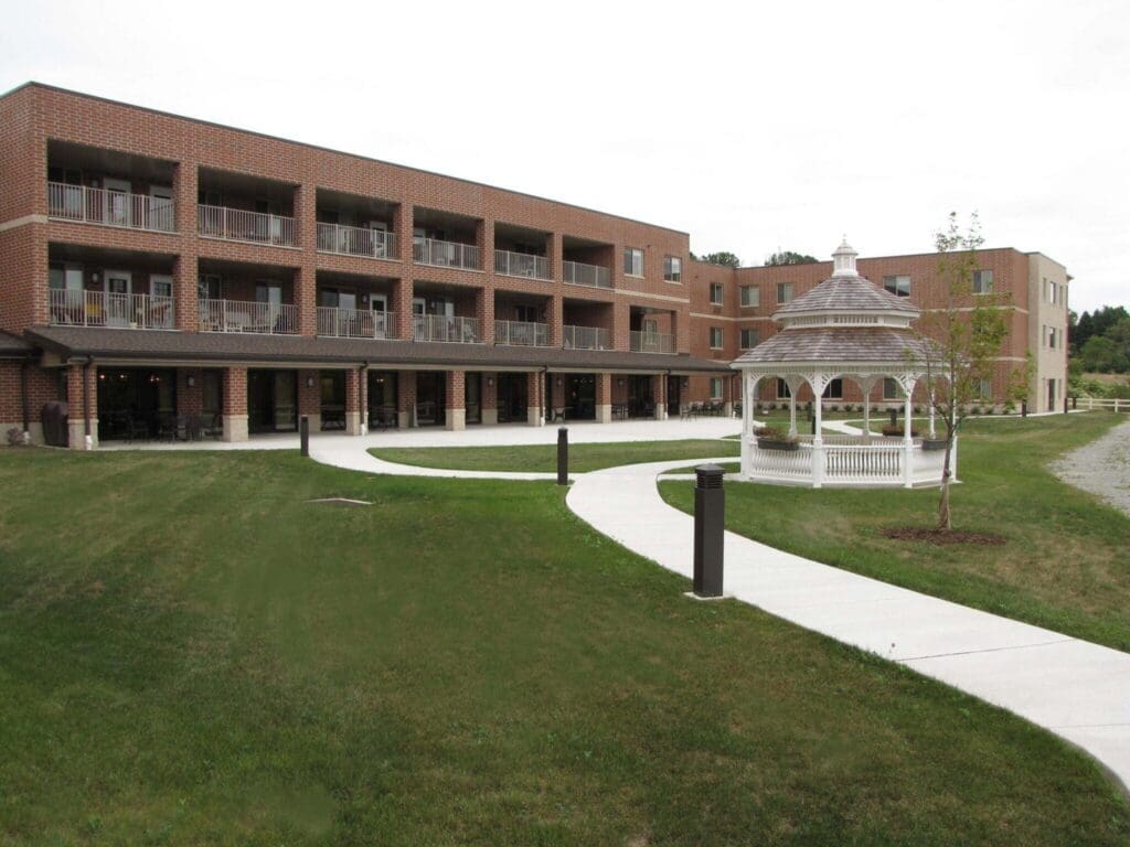 Elegant senior living community featuring spacious balconies, manicured lawns, and a charming gazebo amidst vibrant surroundings.