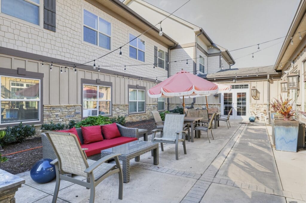 Inviting outdoor patio with stylish seating, vibrant plants, and a shaded area, perfect for relaxation and socializing.